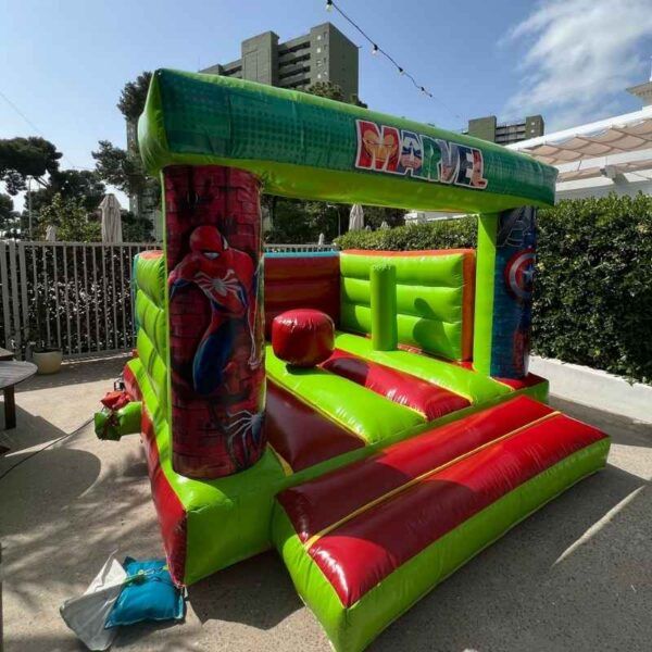 castillo hinchable de alquiler en jardín exterior con temática marvel de color verde y rojo