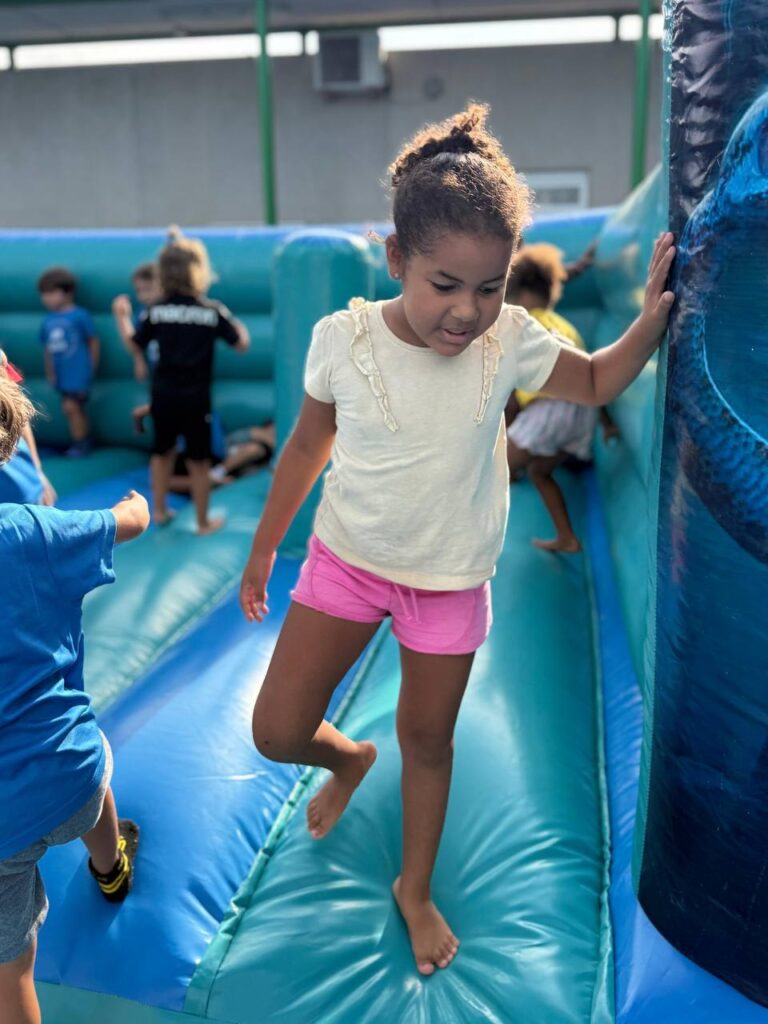 Niña jugando junto a la entrada de un hinchable azul